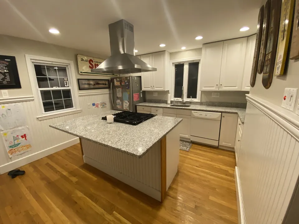 White kitchen island with granite top and cooktop