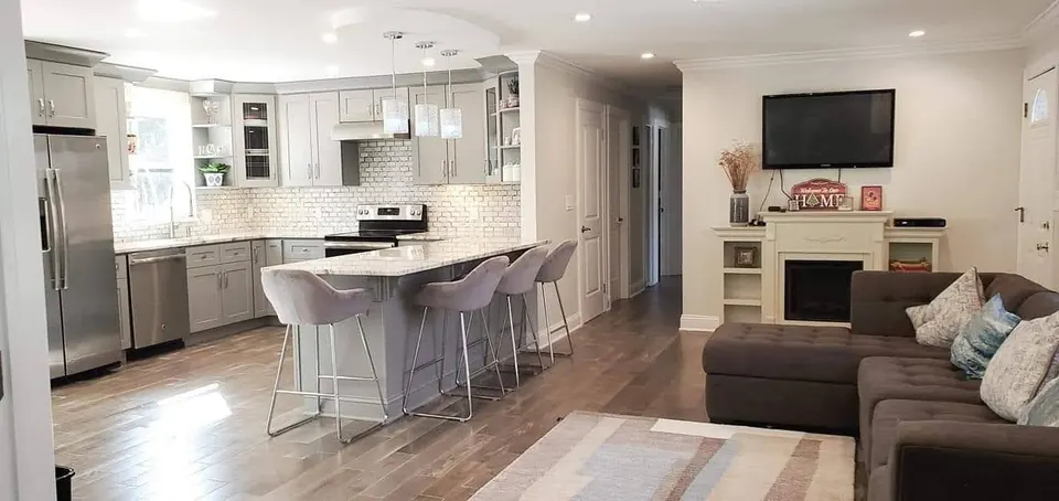 Open gray shaker kitchen and living room with granite peninsula