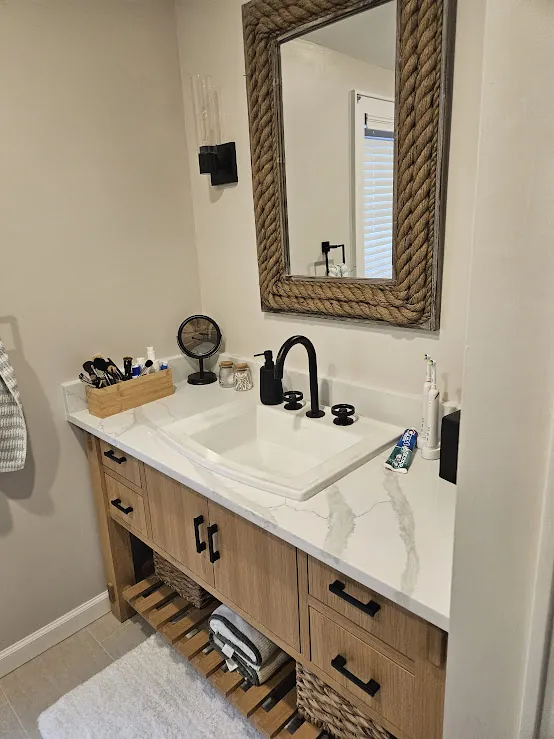 Wood vanity with black faucet and round mirror